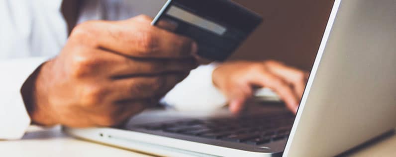 hands of a man using a laptop and holding credit card