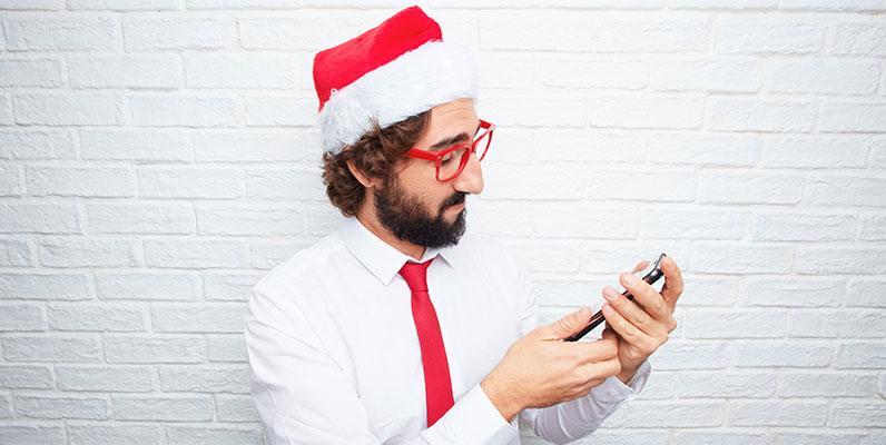 man with santa hat looking at smartphone