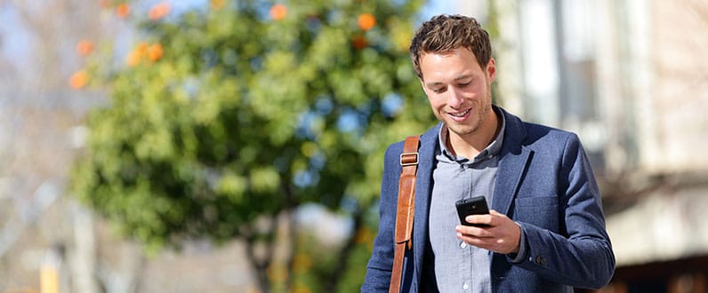 smiling man using his phone in the street