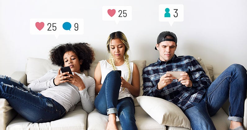 three young people sitting on the sofa and using social media on their phones