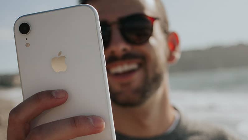 smiling man holding an iphone