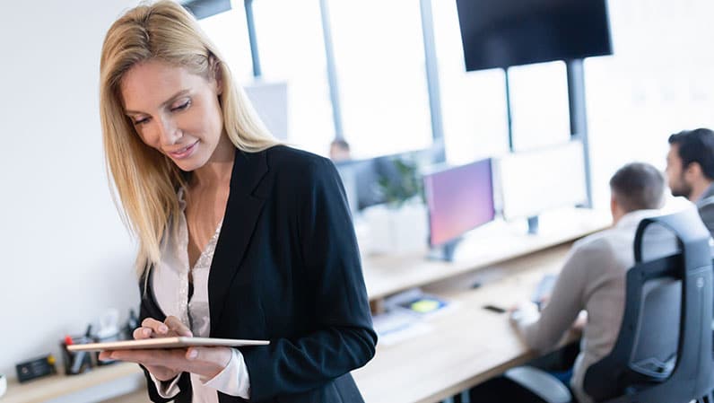 woman in office using a tablet and coworkers behind