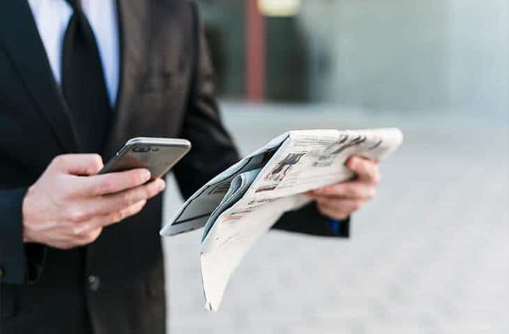 hands holding phone newspaper