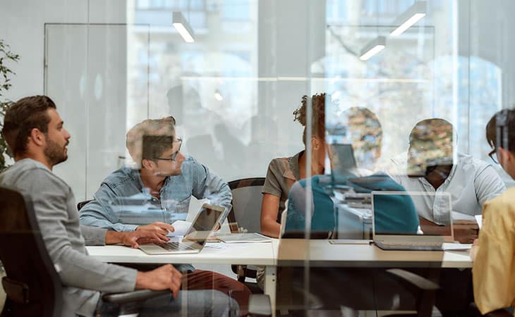 Product Manager Job Description: Guide, Template &Amp; Tips Evinex Corporation | Staffing Agency team working on a big desk
