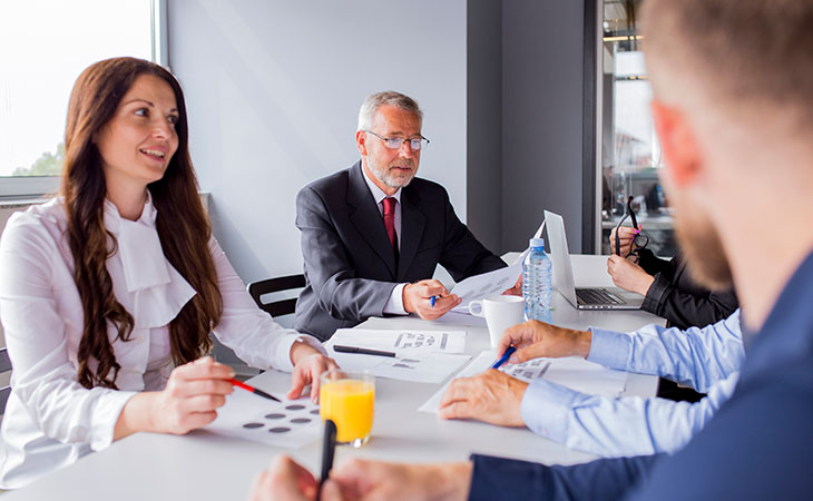 Program Manager Job Description: Essential Skills Guide Evinex Corporation | Staffing Agency group-office-workers-table-meeting