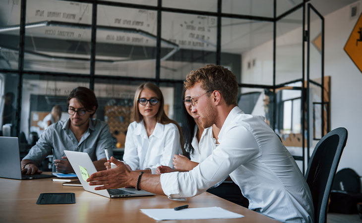 Program Manager Job Description: Essential Skills Guide Evinex Corporation | Staffing Agency three-office-workers-man-pointing-laptop