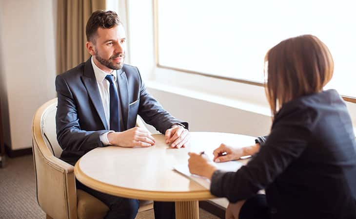100+ Interview Questions For Executives With Sample Answers Evinex Corporation | Staffing Agency woman interviewing a man in a round table