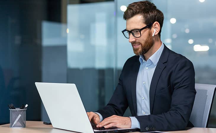 smiling-businessman-using-laptop-headphones