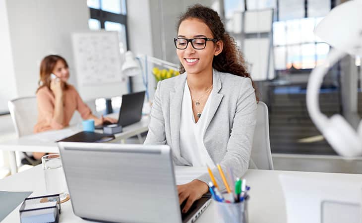 smiling woman in an office using a laptop