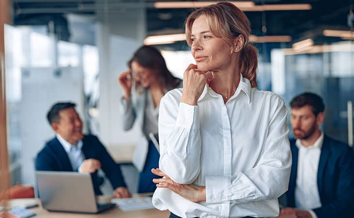 woman thinking with her hand in her chin with people in an office