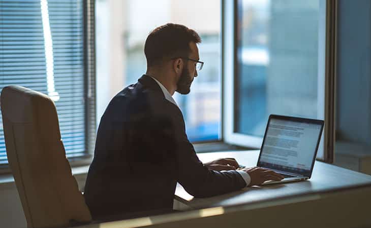man in a suit and glasses using a laptop