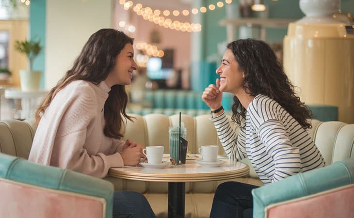 Mastering Interpersonal Skills: Your Guide To Success Evinex Corporation | Staffing Agency two women at a cafe smiling and talking