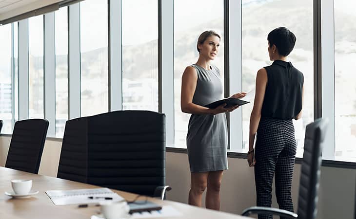 How To Hire An Employee: A Step-By-Step Complete Guide Evinex Corporation | Staffing Agency two women talking at a corporate office