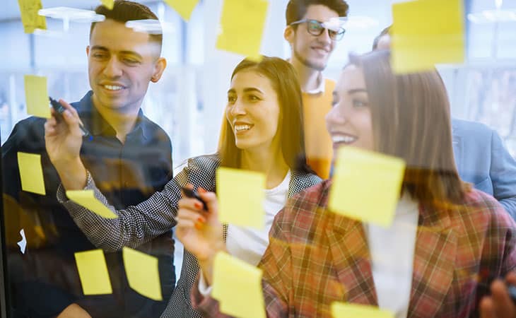 100+ Essential Business Analyst Interview Questions Evinex Corporation | Staffing Agency happy-workers-post-its-glass