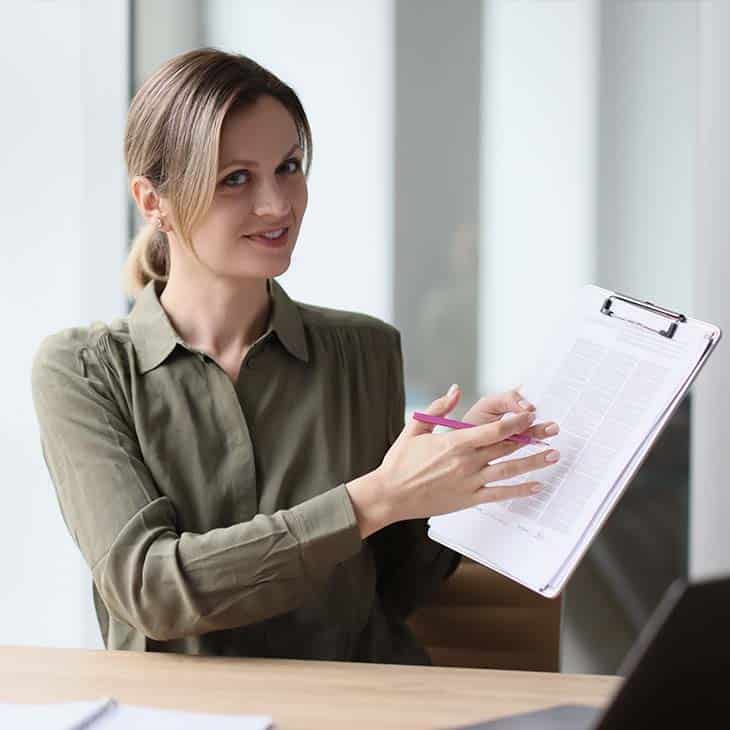 How To Hire An Employee: A Step-By-Step Complete Guide Evinex Corporation | Staffing Agency woman showing papers looking at the camera