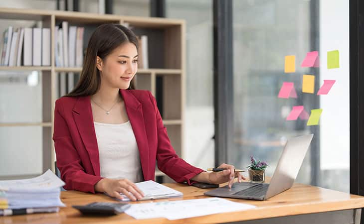 How To Hire An Employee: A Step-By-Step Complete Guide Evinex Corporation | Staffing Agency woman using a laptop with a pen in her hand