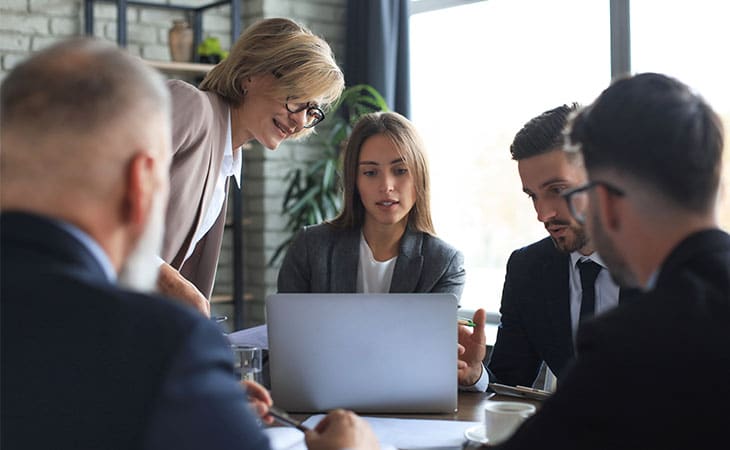 Sales Manager Job Description: Attract And Hire Top Talent Evinex Corporation | Staffing Agency a group of people in an office looking at a laptop