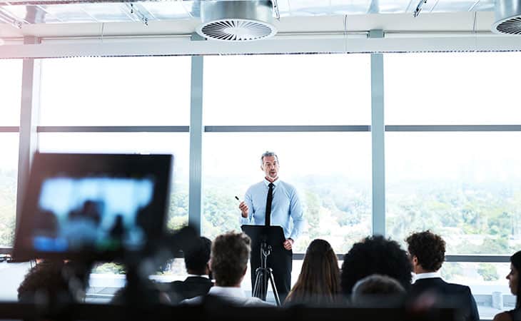 Sales Manager Job Description: Attract And Hire Top Talent Evinex Corporation | Staffing Agency a man giving a speech to people in a workshop