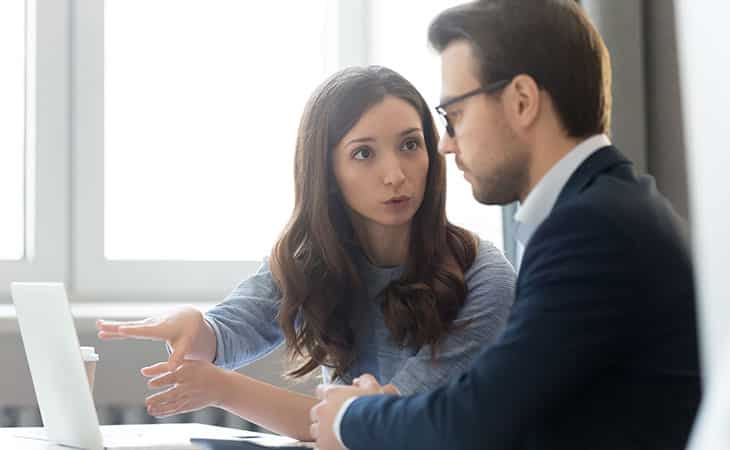 What Is Workforce Management? Key Benefits Evinex Corporation | Staffing Agency a woman talking to a man and pointing at a laptop screen