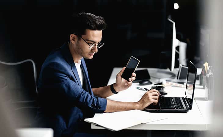 100+ Interview Questions For The Perfect Executive Assistant Evinex Corporation | Staffing Agency man-glasses-holding-phone-laptop