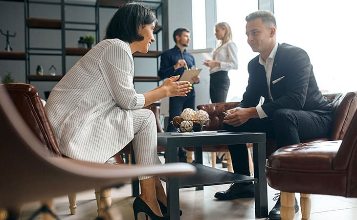 Background Check Questions: A Guide For Effective Hiring Evinex Corporation | Staffing Agency people talking at a table and people in the background