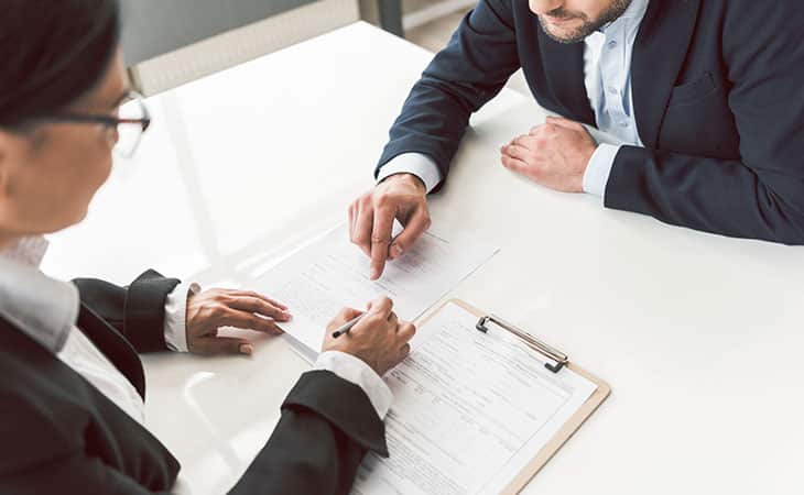 Background Check Questions: A Guide For Effective Hiring Evinex Corporation | Staffing Agency two people pointing at a document