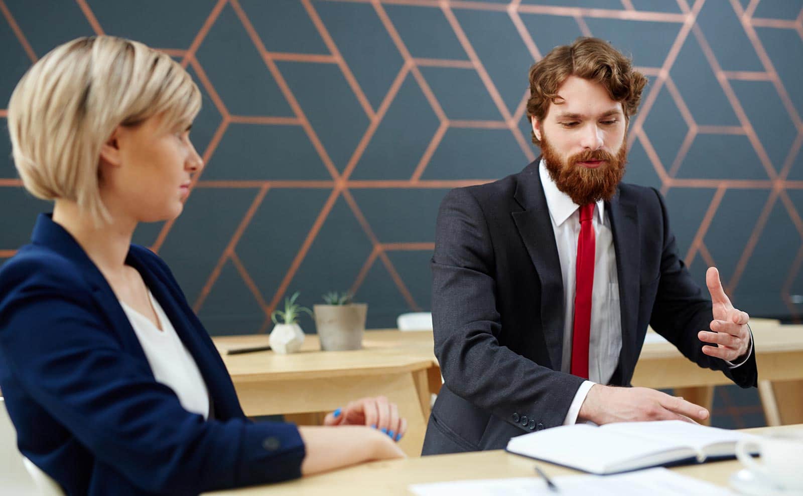 two people wearing suit in an office, talking