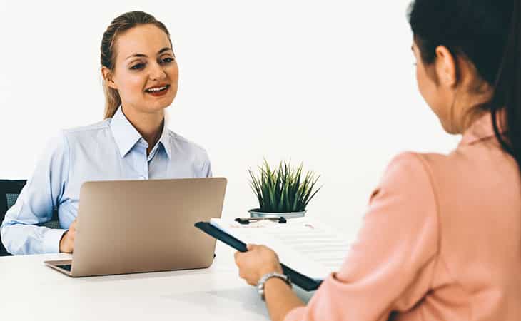 Background Check Questions: A Guide For Effective Hiring Evinex Corporation | Staffing Agency two women talking about documents