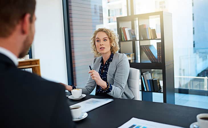 Background Check Questions: A Guide For Effective Hiring Evinex Corporation | Staffing Agency woman pointing with her pen talking to a man