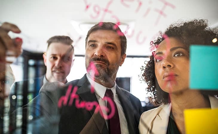 100+ Sales Manager Interview Questions With Answers Evinex Corporation | Staffing Agency a businessman writing in a glass wall and people looking