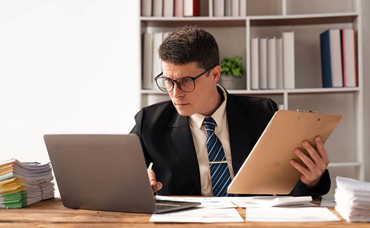 Best Fonts For Your Resume: Stand Out Professionaly Evinex Corporation | Staffing Agency a man in the office looking at a laptop and holding a folder