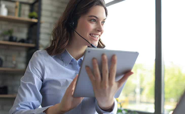 100+ Sales Manager Interview Questions With Answers Evinex Corporation | Staffing Agency a smiling woman using a tablet and headphones