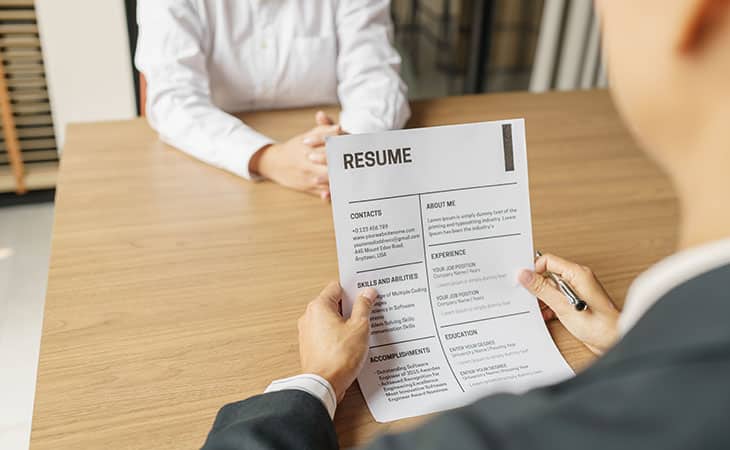 Best Fonts For Your Resume: Stand Out Professionaly Evinex Corporation | Staffing Agency detail of a job interview and a resume in a mans hands