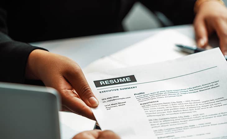 Best Fonts For Your Resume: Stand Out Professionaly Evinex Corporation | Staffing Agency detail of hands holding a resume printed on paper