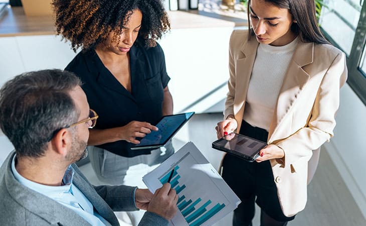 100+ Sales Manager Interview Questions With Answers Evinex Corporation | Staffing Agency three office workers talking and holding papers and tablets