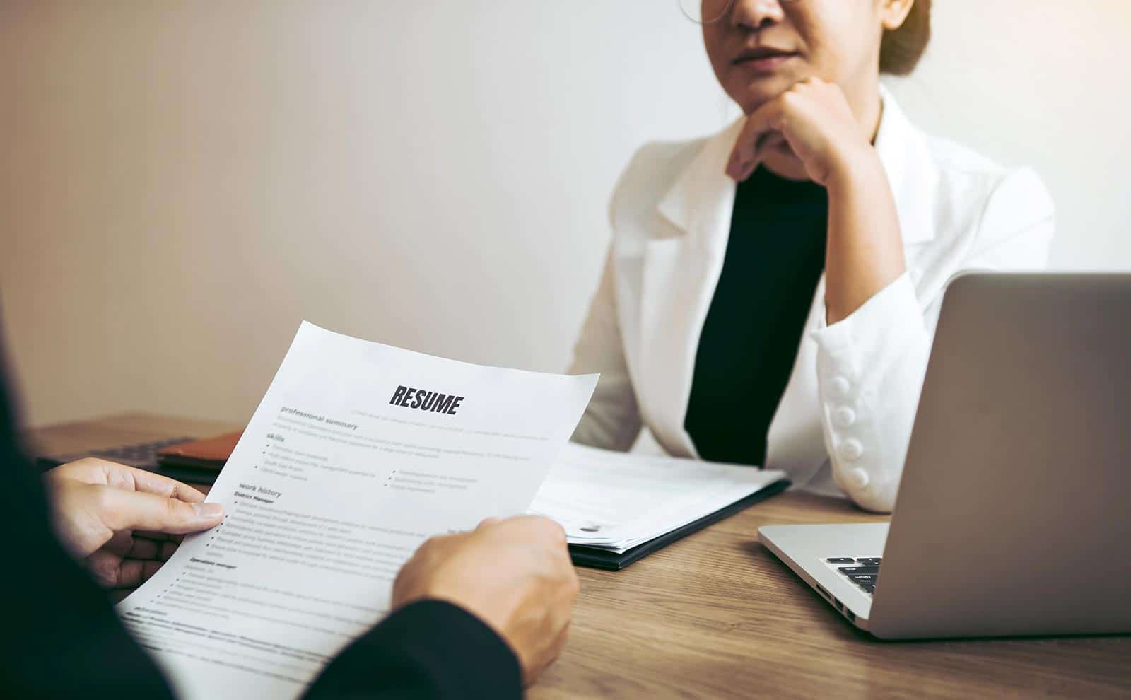 woman talking to a man with a resume in his hands