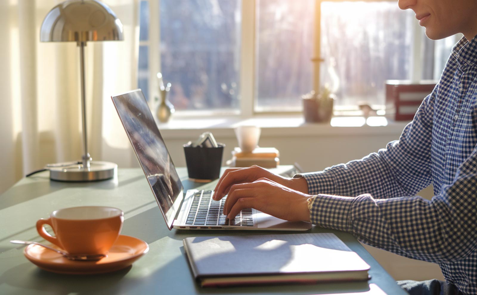 a man wearing shirt typing in a laptop inside a house