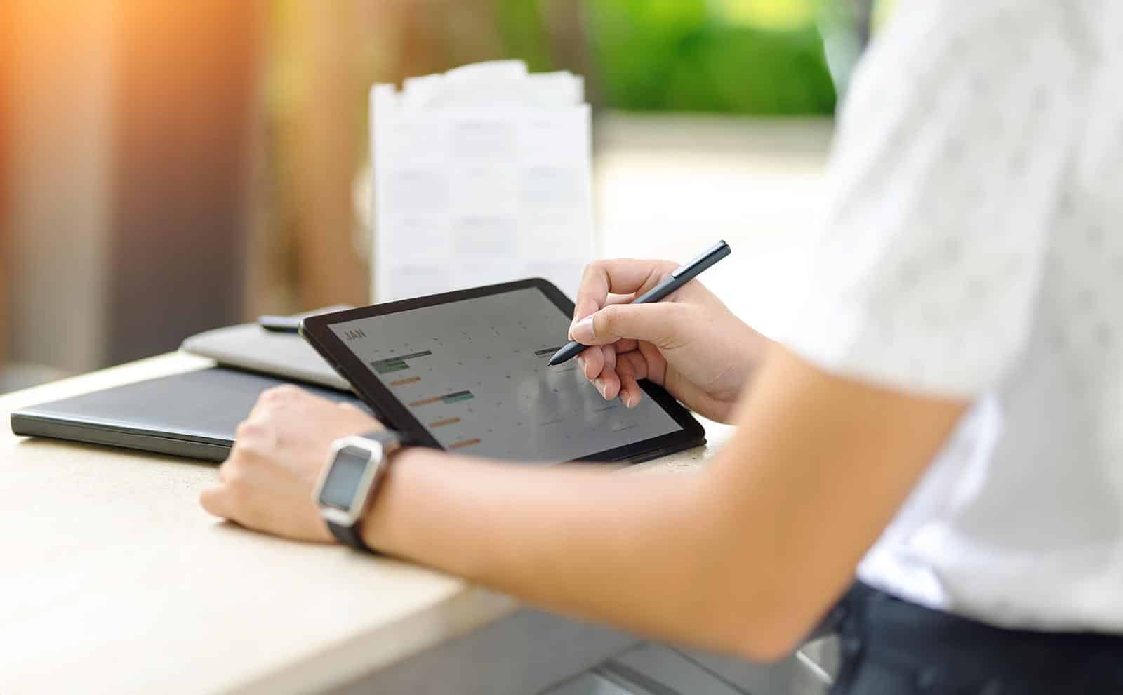 detail of womans arms using a tablet with a timetable