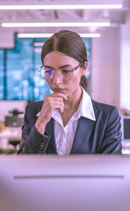 a focused woman watching her computer screen intently