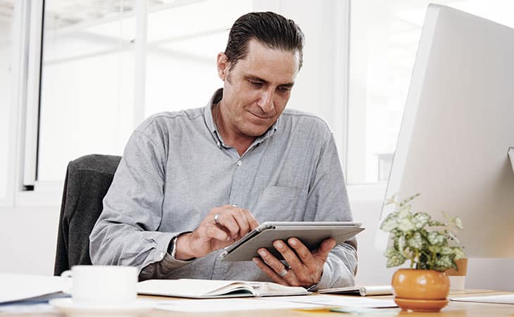 How To Conduct A Job Interview For Better Hiring Decisions Evinex Corporation | Staffing Agency a man using a tablet sitting at an office desk