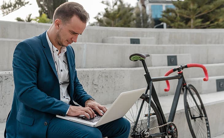 a man with a laptop and a bike is outdoors
