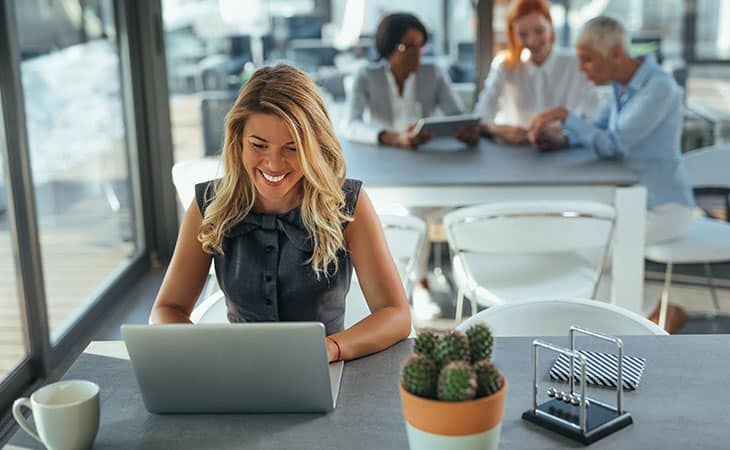 a smiling woman is working on a laptop