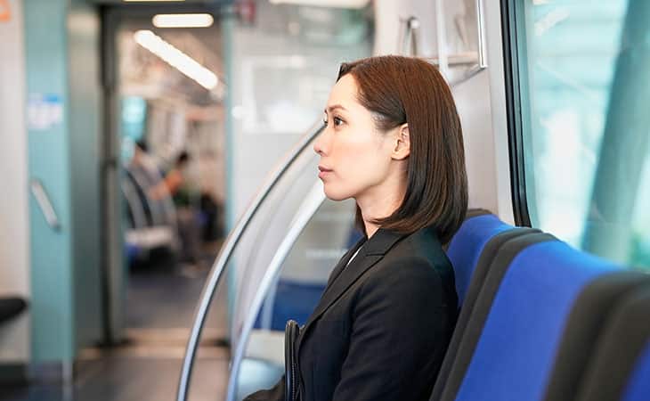a woman is seated in the subway looking thoughtful