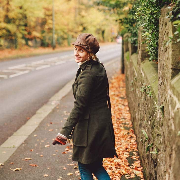 a woman is walking down an autumn street while smiling