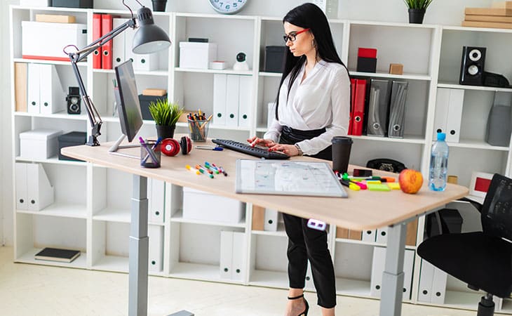 Hr Issues And Challenges: Solutions For The Modern Workplace Evinex Corporation | Staffing Agency a woman working on a computer at an organized standing desk with office supplies around her