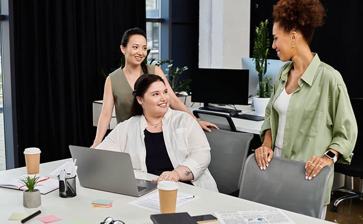 three women discussing work in an office environment