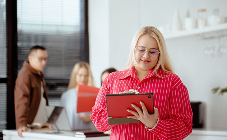 woman in red using a tablet in a group setting