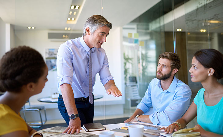 How To Lead A Team: Strategies For Effective Leadership Evinex Corporation | Staffing Agency a businessman talking to his colleagues