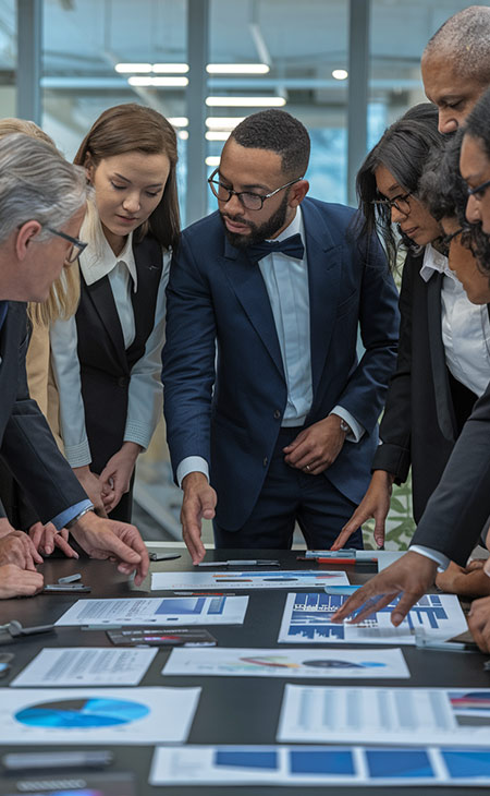 What Is Teamwork And Why Is It Important For Success? Evinex Corporation | Staffing Agency a group of business people talking and pointing at papers