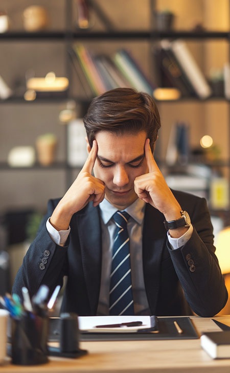 a man in a suit is stressed with his fingers on his head in an office